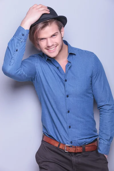 Smiling young man puts on his hat — Stock Photo, Image