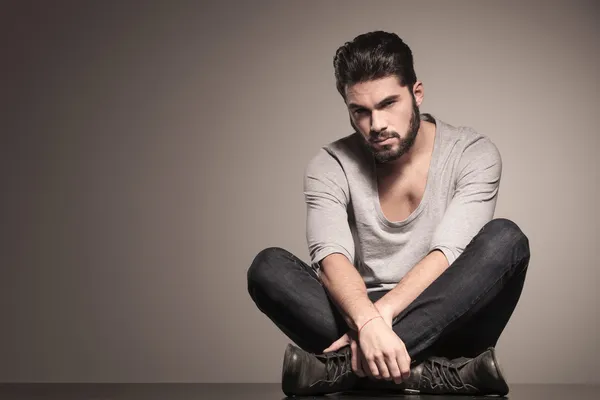 Sérieux homme de mode barbu est assis en position de yoga — Photo