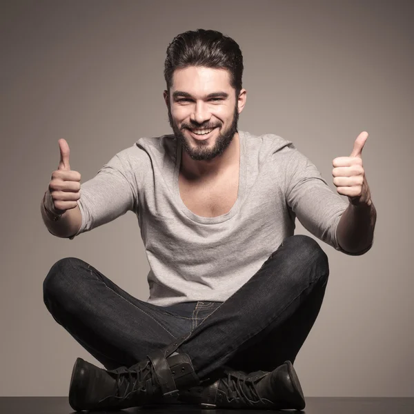 El hombre feliz se sienta y hace la señal de la mano ok —  Fotos de Stock