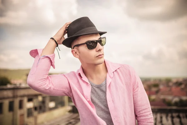 Hombre casual con gafas de sol fijando su sombrero en la cabeza —  Fotos de Stock