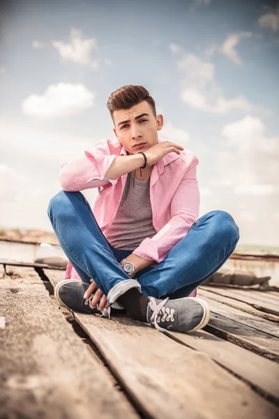 Sentado joven casual hombre haciendo una cara — Foto de Stock