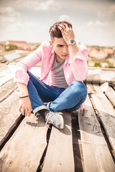 Junger Mann sitzt und fixiert seine Haare — Stockfoto