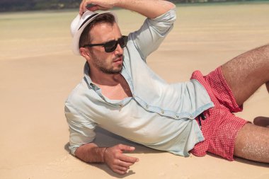 seksi bir adam sahilde şapka tutan ve uzağa arıyorsunuz