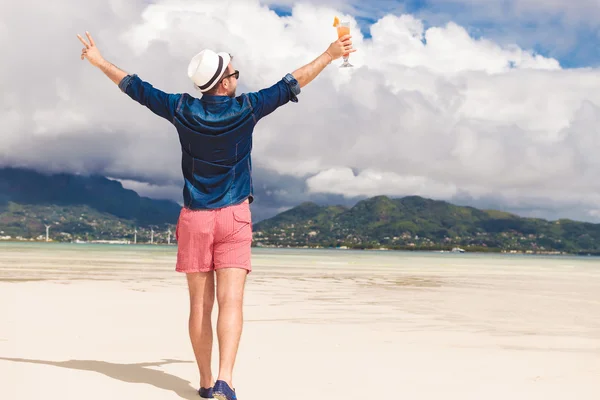 Happy man with hands up holding a cocktail and celebrating — Stock Photo, Image