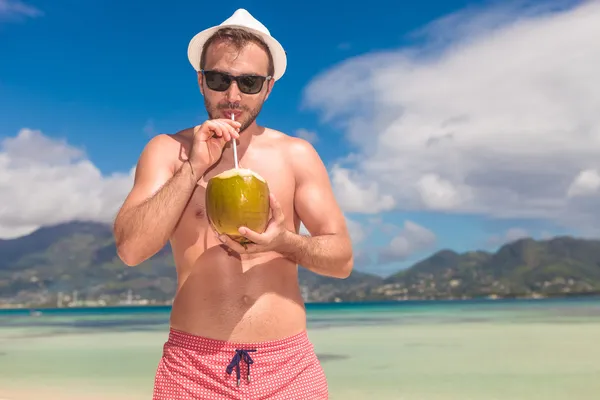 Člověk pije šťávu z výboru matice na pláži — Stock fotografie
