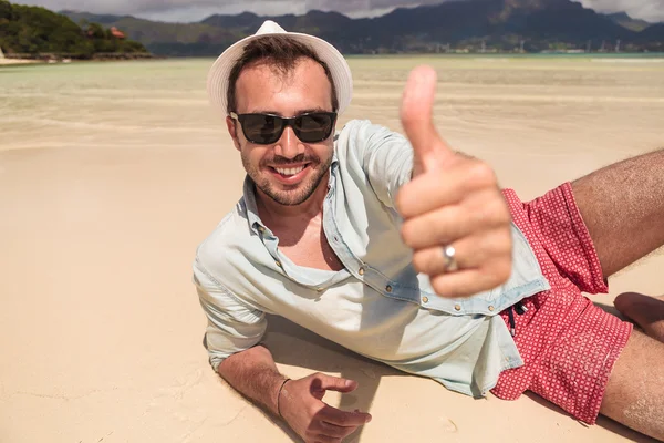 Uomo sdraiato sulla spiaggia e fa il segno ok — Foto Stock