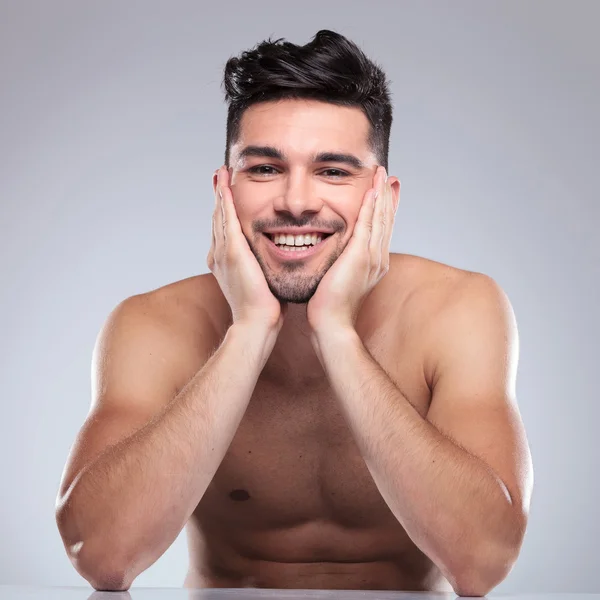 Laughing young man holding his head in  palms — Stock Photo, Image