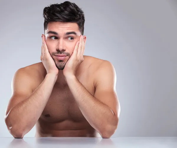 Naked man with head in his palms looking to side — Stock Photo, Image