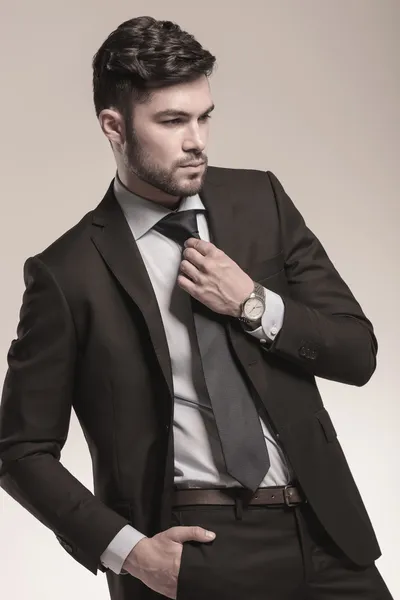 Side view of a young business man fixing his tie — Stock Photo, Image