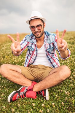 adam bir alan üzerinde oturur ve zafer işareti yapar