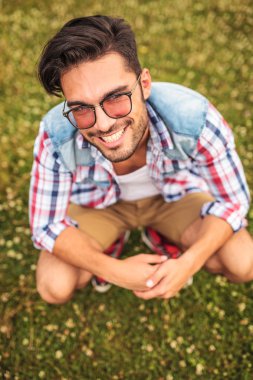 bir çim alanda çömelmiş genç adam