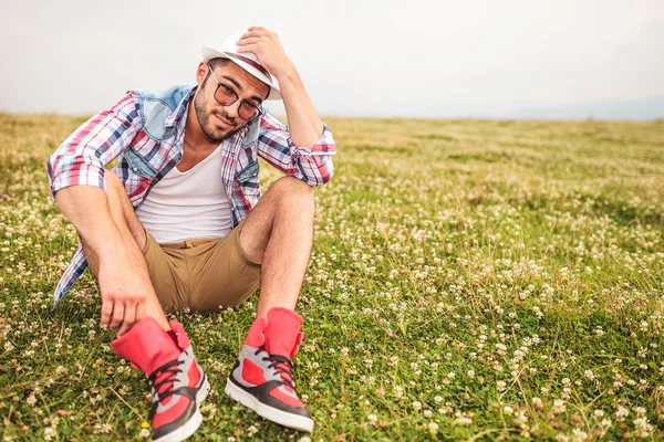 Young man saying hello holding hat — Stock Photo, Image