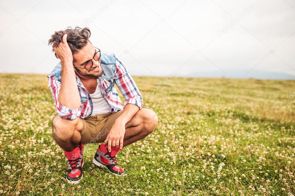 laughing crouched man passing his hand through his hair