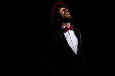 Yakışıklı iş adamı gülüyor ve mutlu hissediyor, siyah arka planda bordo bir şapka takıyor.