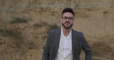 Kendine güveni olmayan, ceplerinde el ele tutuşan, gözlük takan, yürüyüp giden ve sonbahar arkaplanında asker selamı veren bir adam.