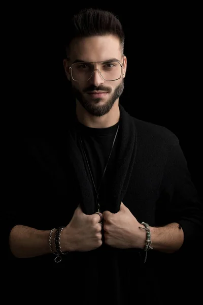 Feliz Misterioso Joven Con Gafas Sosteniendo Ajustando Chaqueta Negra Sonriendo —  Fotos de Stock