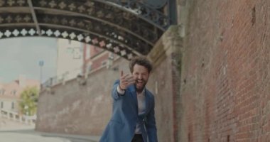 Çekici bir iş adamı elini düğmeye basıyor sonra birini davet ediyor, işaret ediyor, uzaklaşıyor ve araştırıyor.