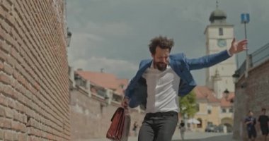 Yakışıklı iş adamı zıplıyor, dans ediyor, çığlık atıyor ve elinde bir evrak çantası tutuyor.