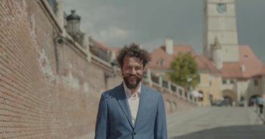 İş adamı, şehirde, dışarıda kameraya gülümsüyor.