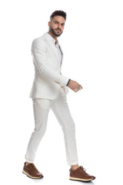 Yakışıklı bir iş adamının beyaz arka planda yürürken diğer tarafa bakışının yan görüntüsü