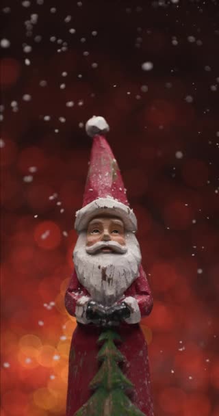 Снег Падает Деревянную Рождественскую Статуэтку Санта Клауса Фоне Боке Красных — стоковое видео