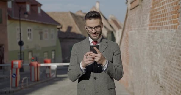Uśmiechnięty Elegancki Mężczyzna Garniturze Długim Płaszczem Trzymający Telefon Czytający Maile — Wideo stockowe