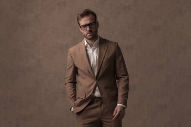 young handsome businessman posing with one hand in pocket and looking deep at the camera