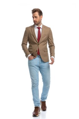 handsome businessman looking to the side, walking with one hand in pocket against white background