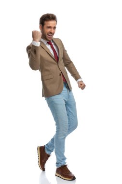 side view of an excited businessman celebrating success and walking on his way against white background