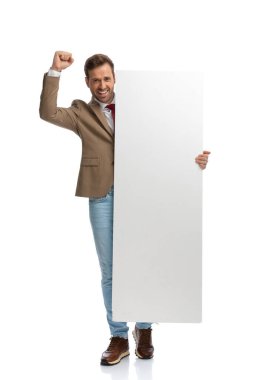 sexy businessman celebrating success and holding a blank board against white studio background