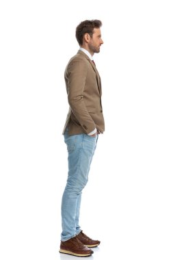 side view of a handsome businessman posing with his hands in his pockets and waiting in line