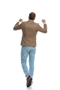 rear view of a businessman walking away from the camera and celebrating success against white background