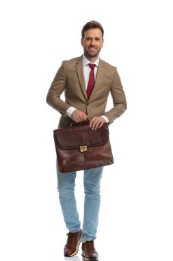 young handsome businessman walking towards the camera with a briefcase and a smile on his face
