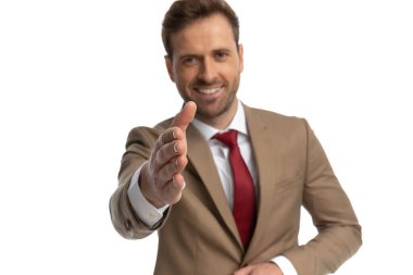 sexy businessman wearing a suit, shaking hands and smiling at the camera on white background