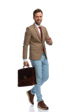 young happy businessman pointing at the camera while walking and smiling against white background