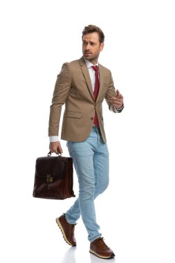 young fashion model walking one way and pointing the other while holding a briefcase