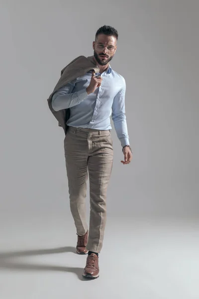Confident Young Man Holding Jacket Shoulder Walking Grey Background Studio — Stock Photo, Image