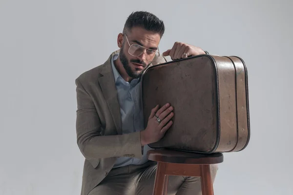 Young Fashion Model Beard Posing Holding Suitcase Wooden Chair Grey — Zdjęcie stockowe