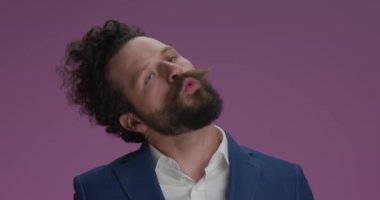 mad businessman with beard and curly hair being crazy, making idiot faces, yelling, looking to side in front of purple background