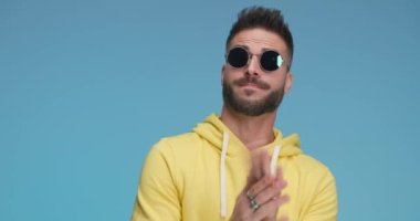 casual man clapping repeatedly, smiling, wearing sunglasses and giving one last powerful clap