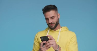handsome casual man writing a message on his mobile phone, feeling happily surprised and gesturing call me