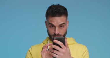 young casual man looking at his phone and cannot believe what he sees, dancing and celebrating success