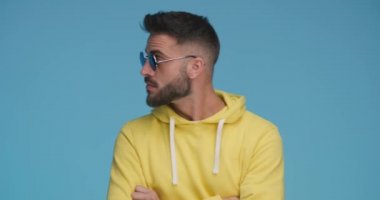 sexy casual man crossing his arms, looking to the side, raising his sunglasses, pointing finger and clapping