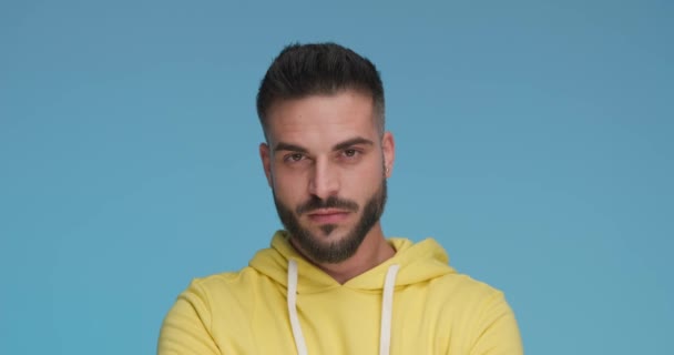 Young Casual Man Smiling Camera Wearing Yellow Hoodie Blue Background — стоковое видео