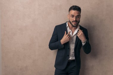 Seksi iş adamı yakasını düzeltiyor, gözlük takıyor ve moda pozu veriyor.