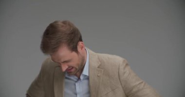 İş adamı nefes alıyor, gri arka planda göğsünde bir ağrı hissediyor.