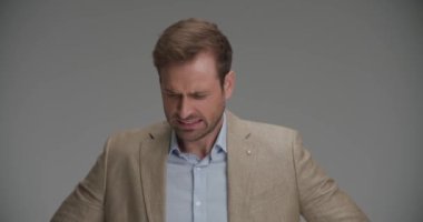 İş adamı yavaş yavaş gri arka planda kalp krizi geçiriyor.