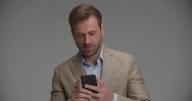 Genç işadamı telefonunda onu gri arka planda güldüren bir şey okuyor.