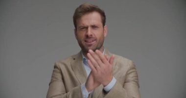 İş adamı ellerini çırpıyor ve gri arka plana tezahürat yapıyor.