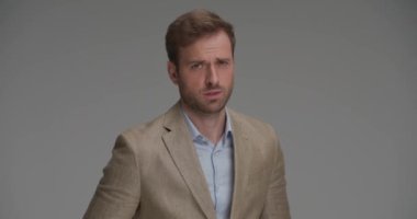 Genç yakışıklı işadamı takım elbisesini düzeltiyor, başka tarafa bakıyor ve tavırlarıyla poz veriyor.